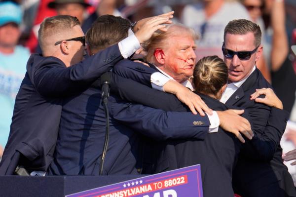 Former President Do<em></em>nald Trump surrounded by U.S. Secret Service agents, being helped off the stage at a campaign rally in Butler, PA, July 13, 2024